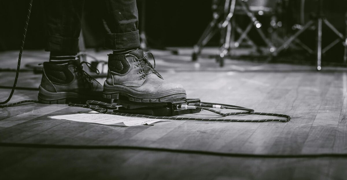 Black and white image of a performer using guitar pedal at a live concert