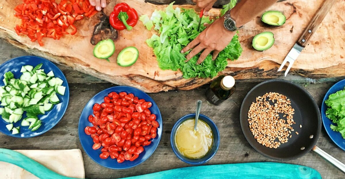 Fresh ingredients being prepared on a rustic wooden table showcasing vibrant vegetables and hands at work