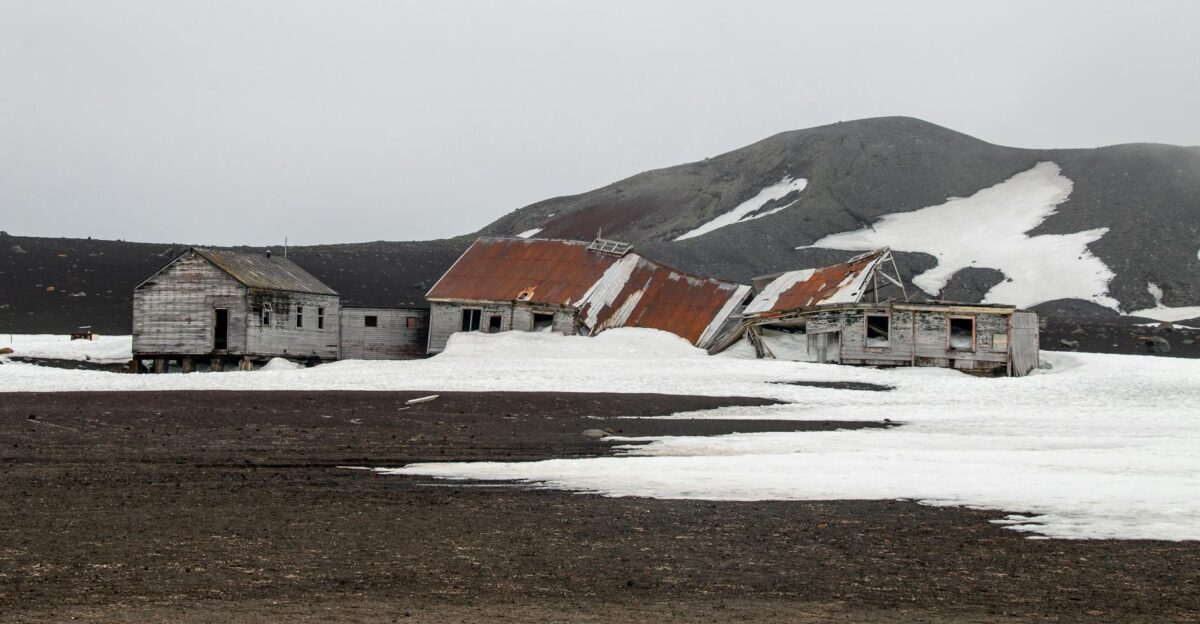 Photograph of abandoned whaling station ruins amidst icy and volcanic landscape in Antarctica