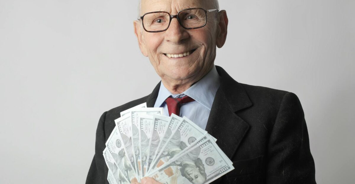 Senior man in a suit with glasses holding US dollars symbolizing wealth and savings