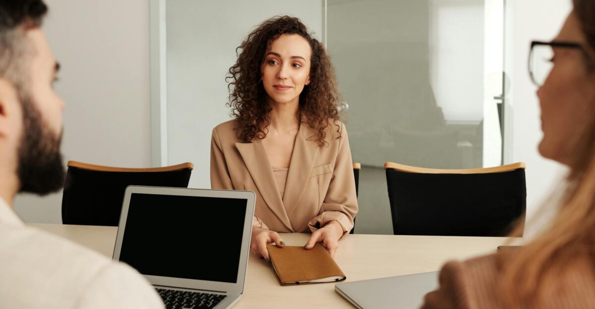 A woman in a business suit participates in a job interview showcasing professionalism and modern office environment