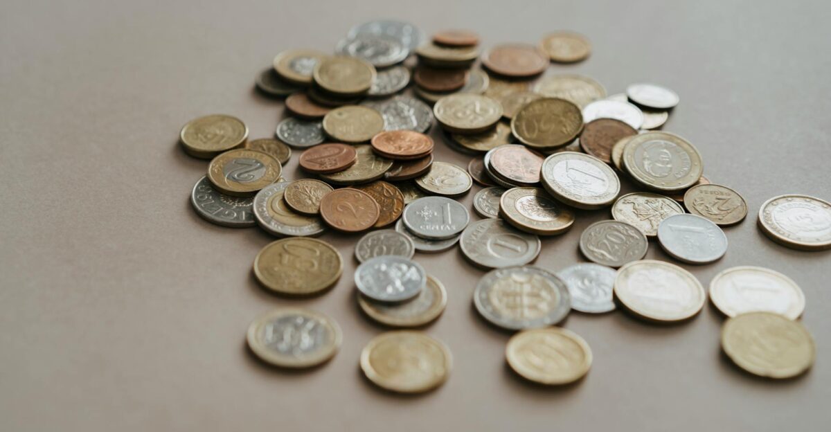 A variety of coins scattered on a neutral surface in soft lighting