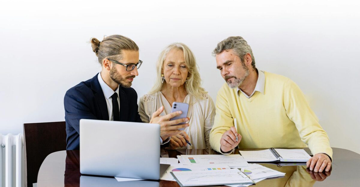 Three individuals collaborating on financial documents during a business meeting