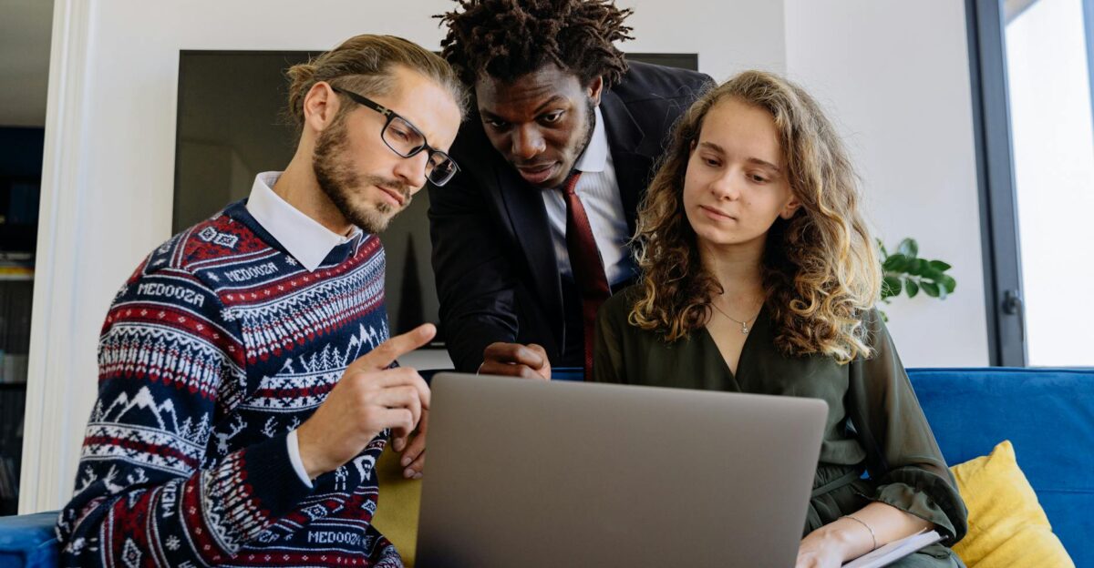 A diverse team of professionals collaborating on a laptop in a modern office setting