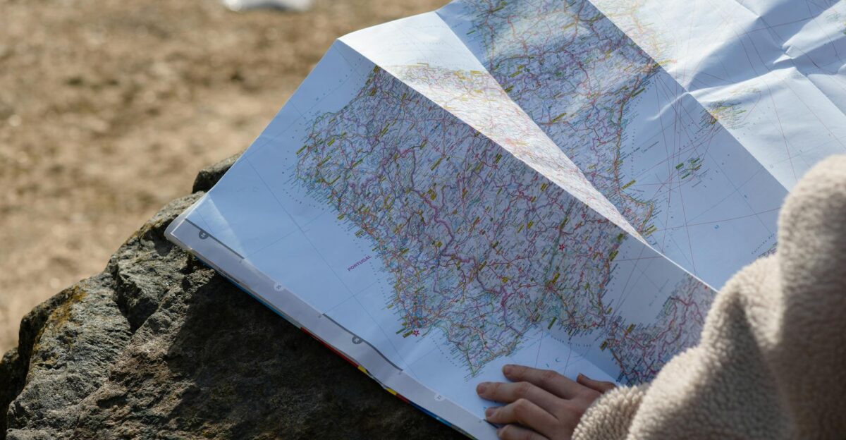 A person studies a roadmap placed on a rock embraced by natural sunlight outdoors