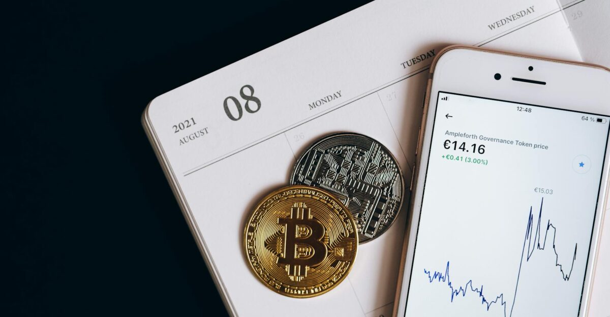 A smartphone displays cryptocurrency data alongside Bitcoin and Ethereum coins on an August calendar