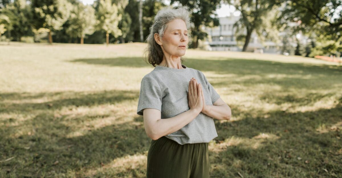 Elderly woman meditating and practicing yoga in a sunny park embracing wellness and mindfulness