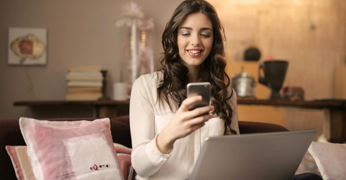 A woman enjoying leisure time using her smartphone and laptop in a cozy living room