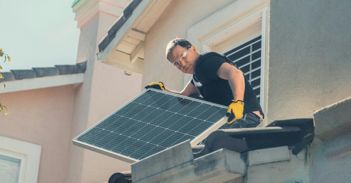 A technician in protective gear installs solar panels on a house roof promoting sustainability