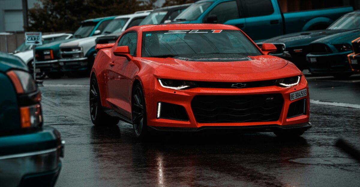 red sports coupe surrounded by vehicles
