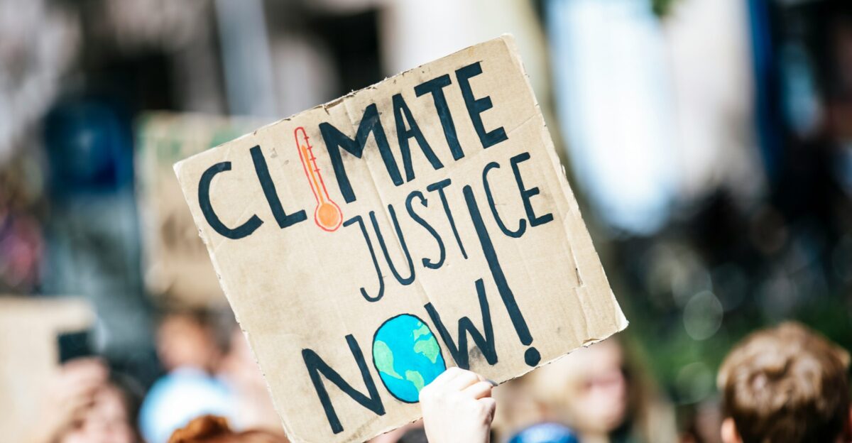 people gathered outside buildings holding Climate Justice Now signage
