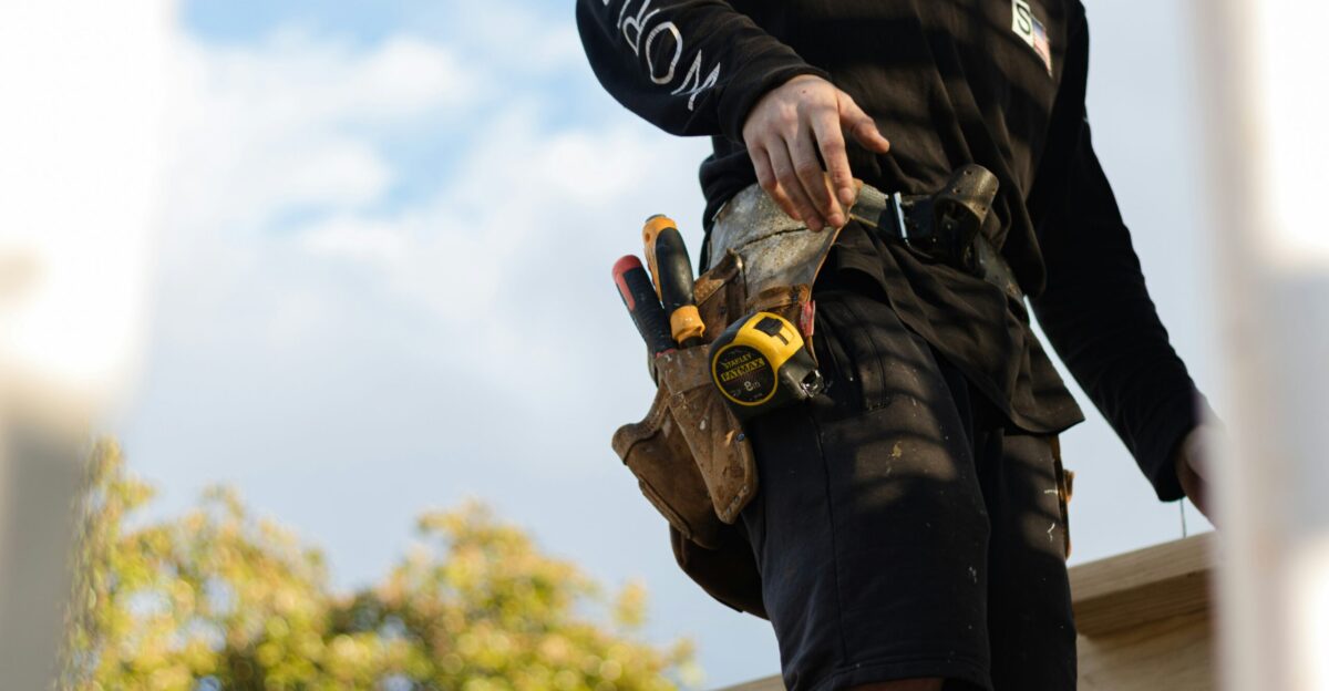 person in black leather jacket holding brown and black hiking shoes