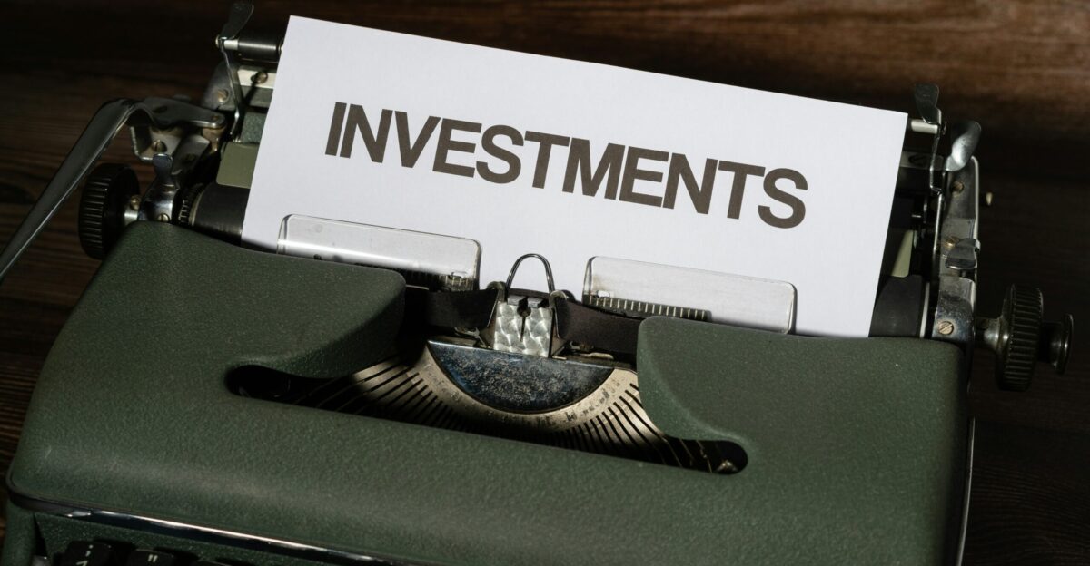 a close up of a typewriter with a paper that reads investments