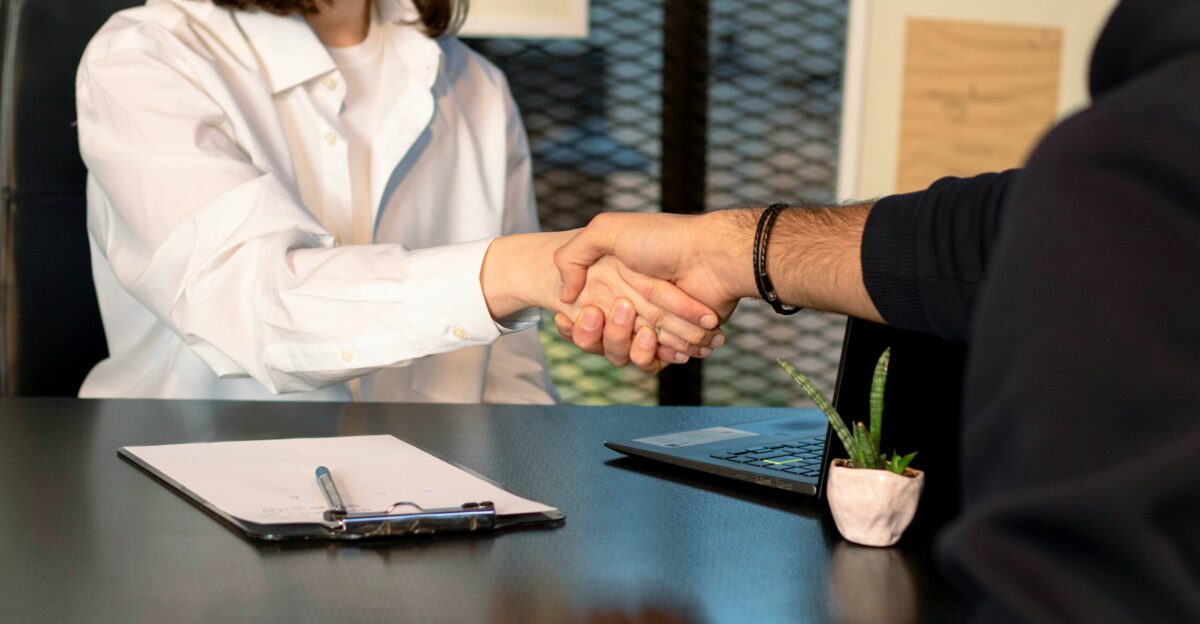 a man and a woman shaking hands in front of a laptop