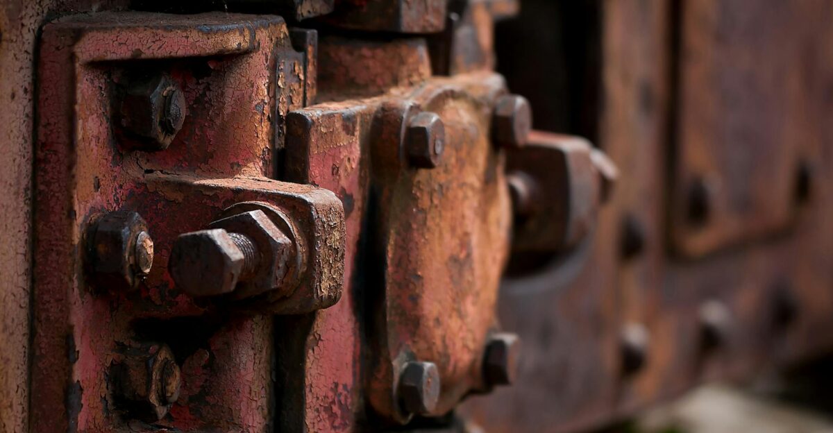 Detailed close-up of corroded metal bolts and plates on a train surface showing aged texture