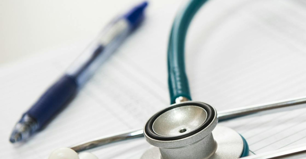 A stethoscope and pen resting on a medical report in a healthcare setting