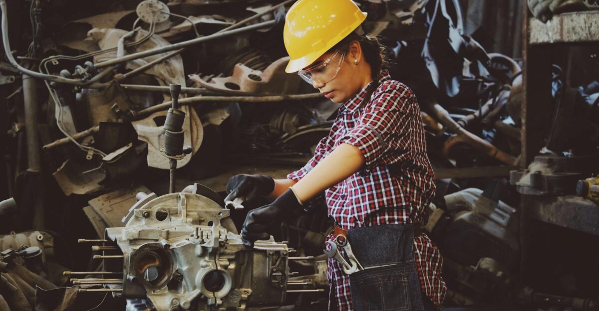 Woman engineer wearing safety gear working on machine repair in an industrial setting