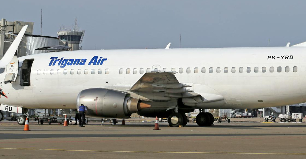 Trigana Air airplane on airport runway during daytime Clear sky and terminal in background