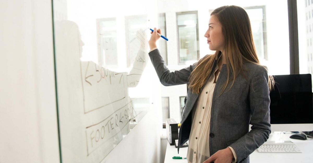Professional woman writing on a whiteboard in an office environment focusing on ideas