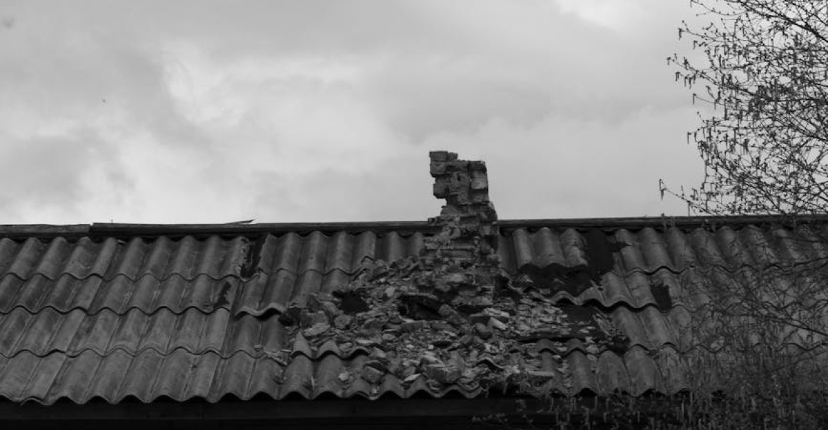 Moody black and white image of an abandoned house with a damaged corrugated roof