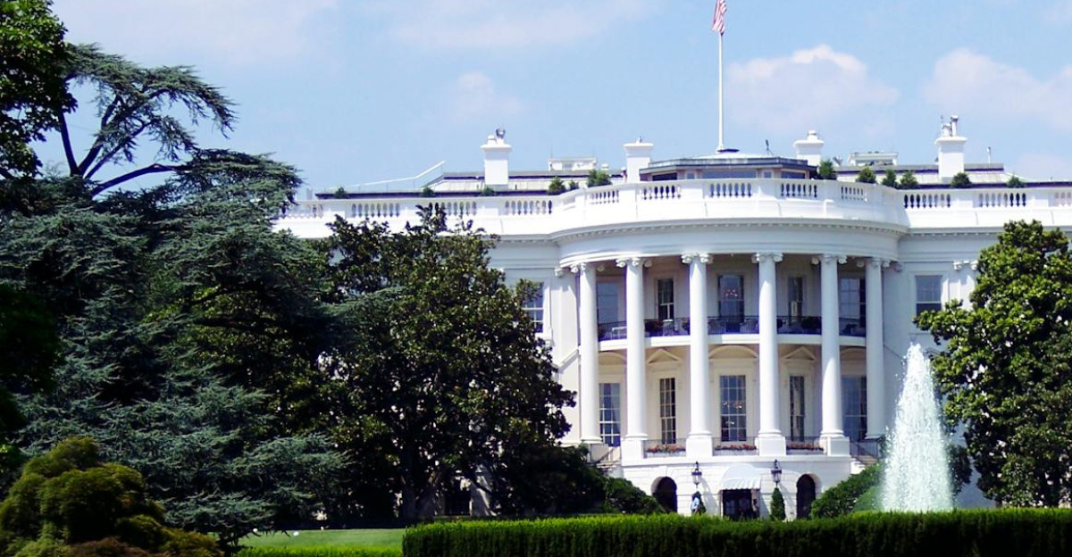 Iconic view of the White House with lush gardens and a central fountain on a sunny day