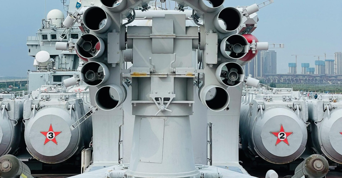 Close view of a battleship's cannons in Tianjin harbor, showcasing military might under a blue sky.