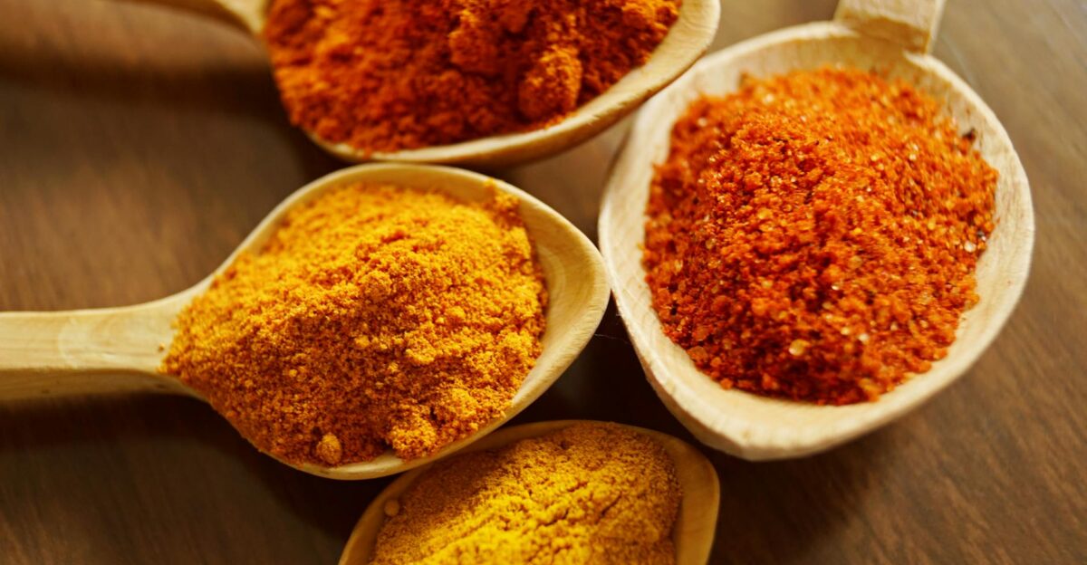 Close-up of vibrant spices like turmeric and chili powder in wooden spoons