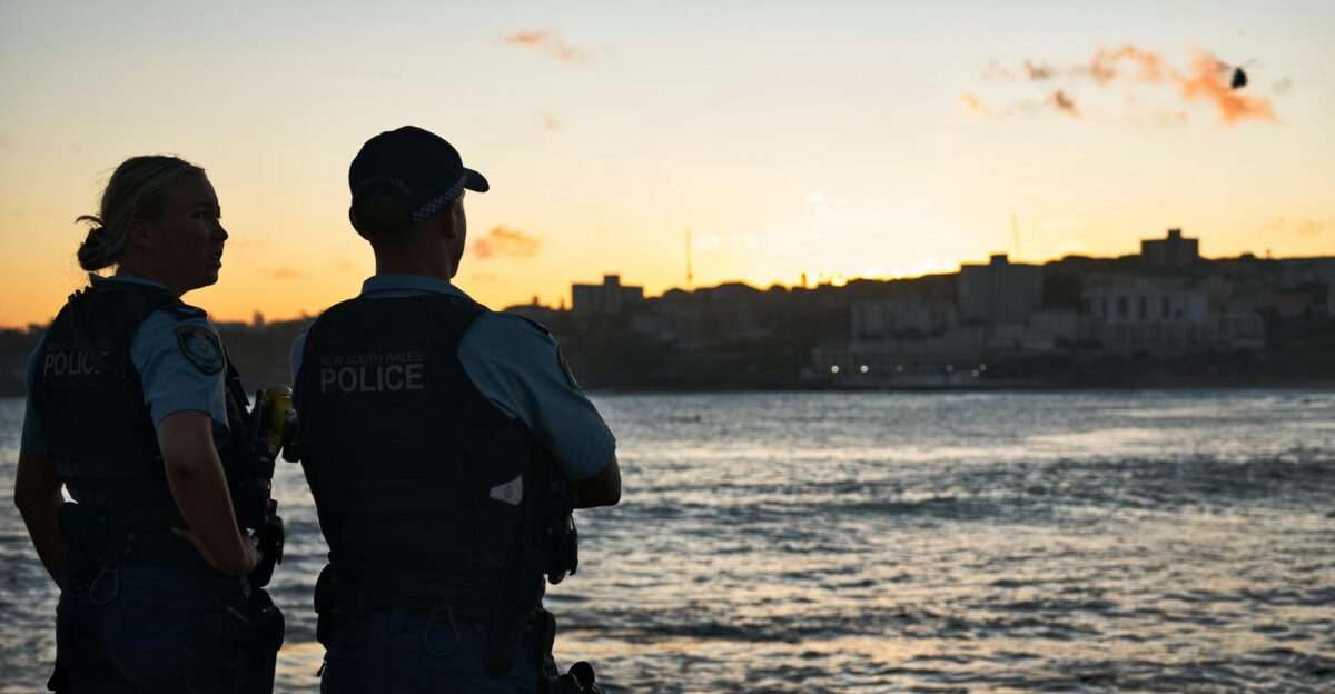 Two police officers in uniform watch the sunset over Bondi Beach NSW Australia