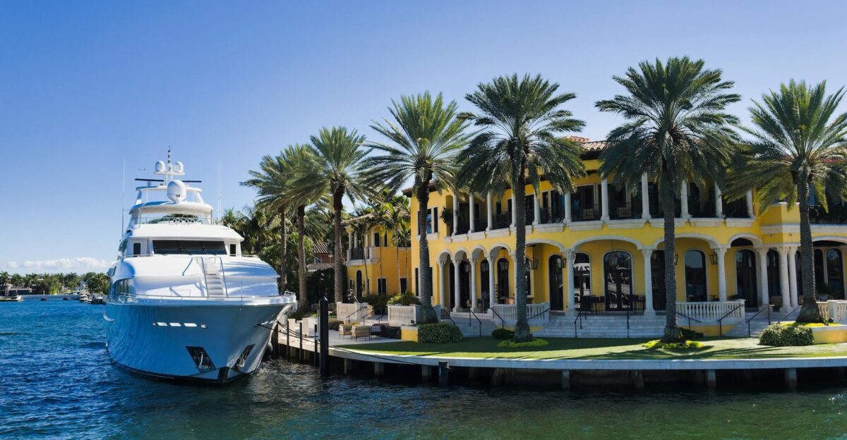 A stunning view of a luxury yacht docked beside a grand mansion in Fort Lauderdale Florida
