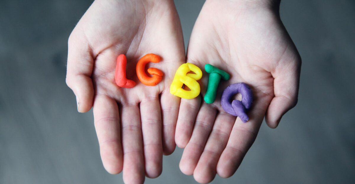 Close-up of hands holding colorful letters representing LGBTQ pride
