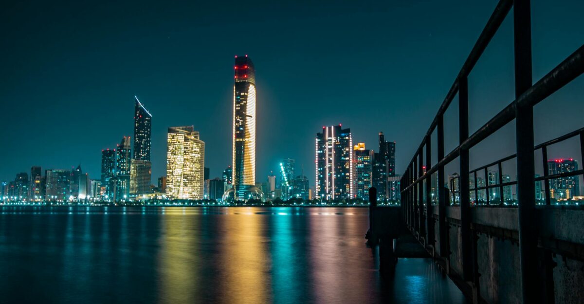 Stunning Abu Dhabi skyline at night with city lights reflecting off the calm waterfront