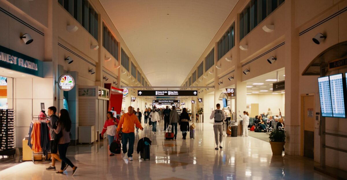 Crowds navigating a bright and busy airport terminal hallway capturing travel dynamics indoors