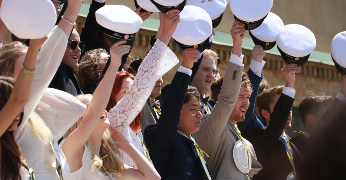 Celebratory graduation moment with students holding caps in joyful cheer