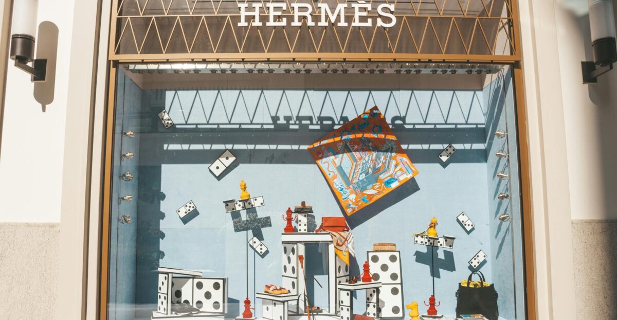Artistic window display at a Hermes store featuring domino-themed decor and luxury items