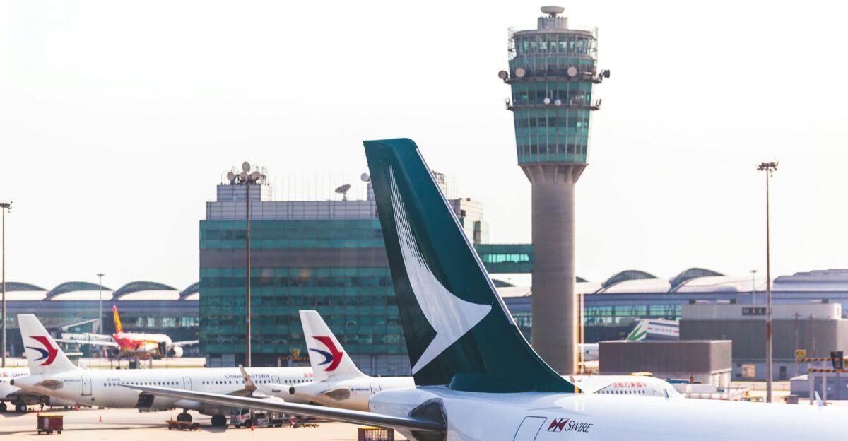 Airplane tailfin and control tower in view at a busy airport terminal