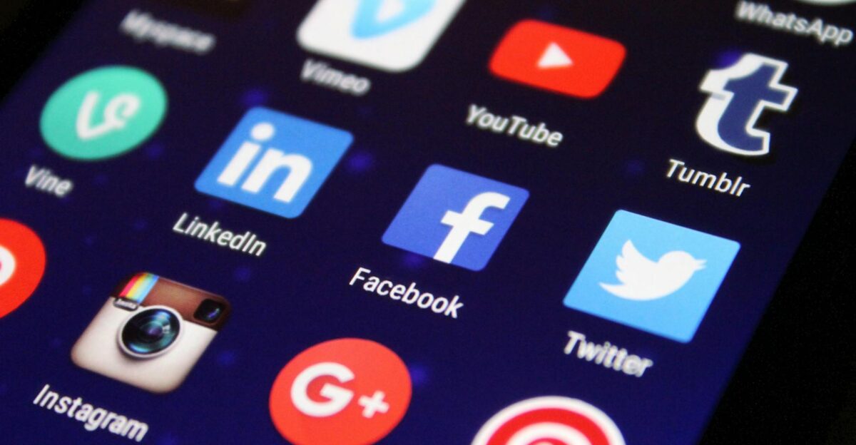 Close-up of a smartphone screen showing various social media app icons such as Facebook and Twitter