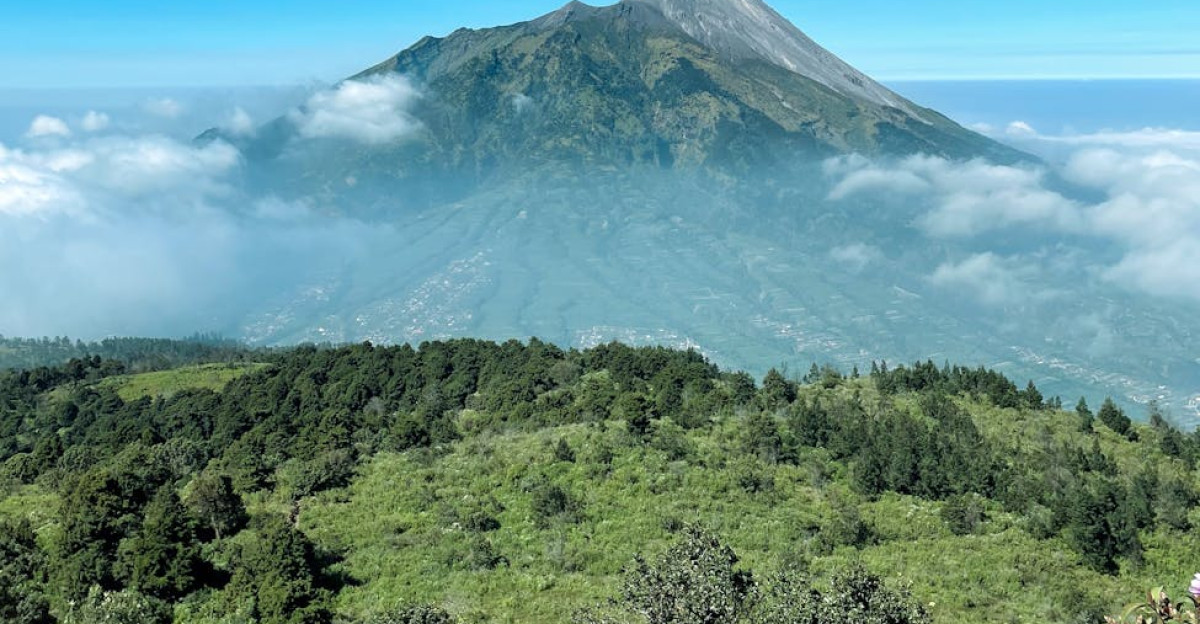 A breathtaking view of Mount Merapi with lush greenery and clear blue skies