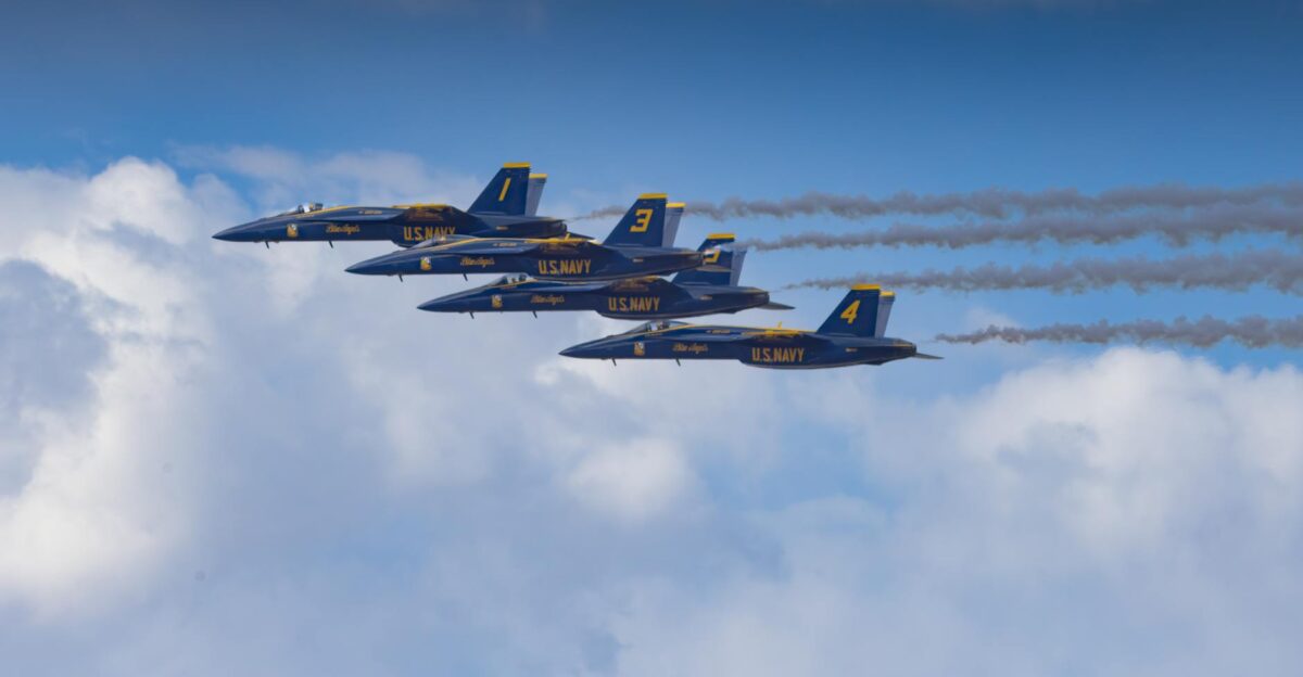 US Navy Blue Angels perform a precision jet formation flying in clear blue skies leaving vapor trails
