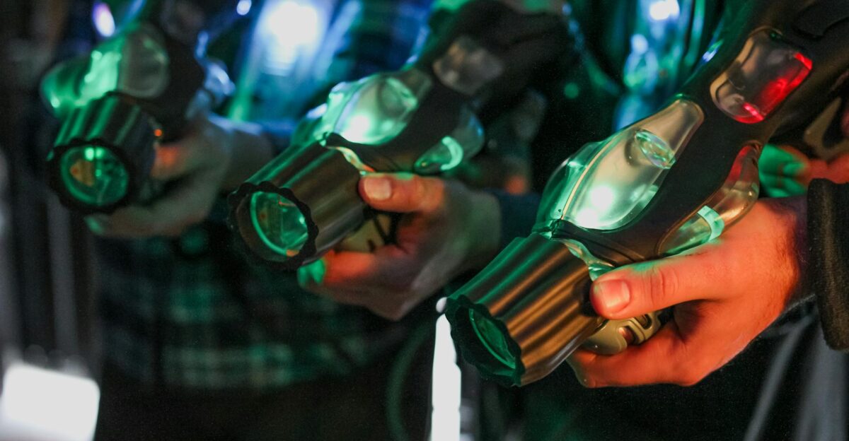 Close-up of players holding illuminated laser tag guns indoors