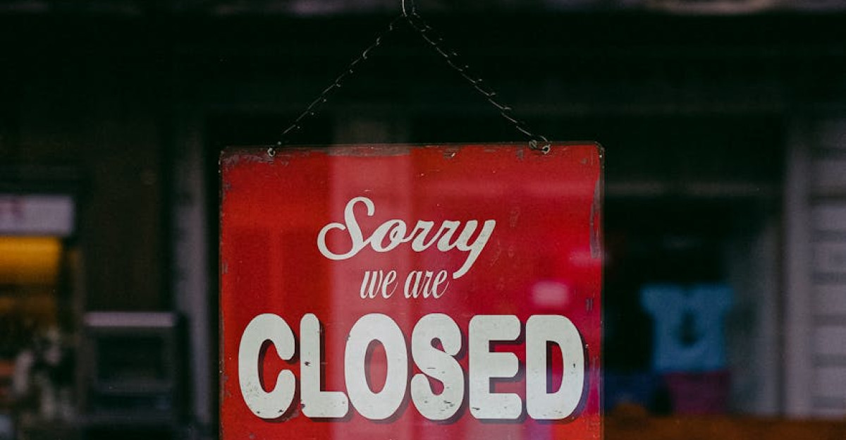Red Sorry We Are Closed sign displayed in a shop window indicating closure