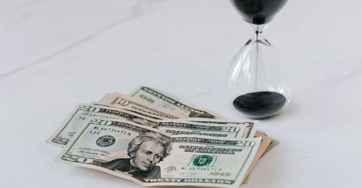 Close-up of US dollar bills with an hourglass symbolizing time and money