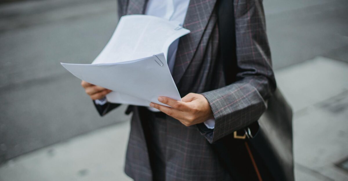 Professional businesswoman reviewing documents outdoors in a city environment