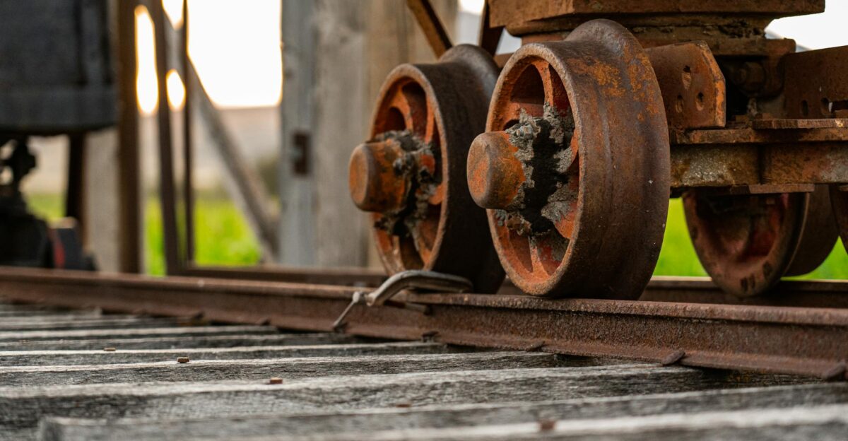 Detailed view of a rustic rail cart wheel resting on an aged track with warm lighting