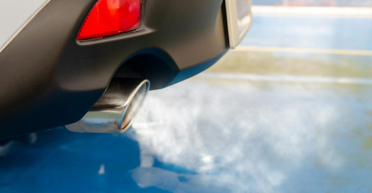 A close view of a car s exhaust pipe emitting smoke on a sunny day highlighting pollution
