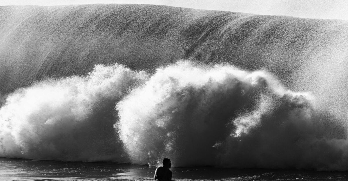 Silhouette of a person facing a large ocean wave in Hawaii capturing the raw power of nature