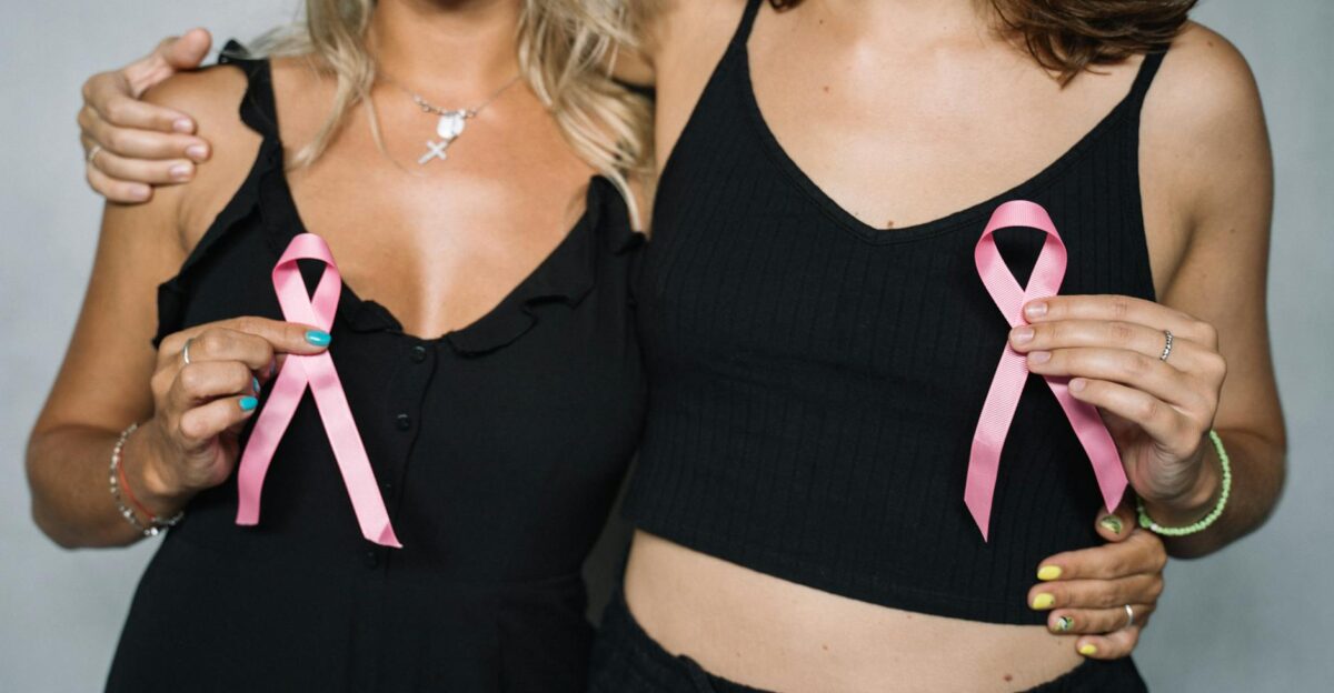 Two women showing support for breast cancer awareness by holding pink ribbons