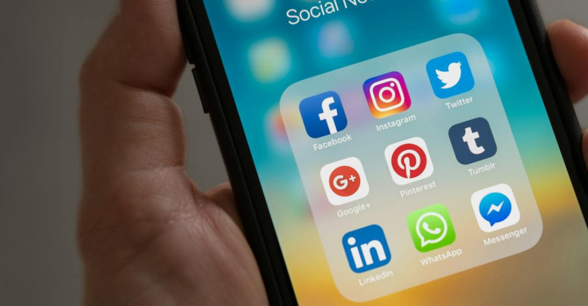 A smartphone displaying various social media icons held in a hand showcasing modern communication apps