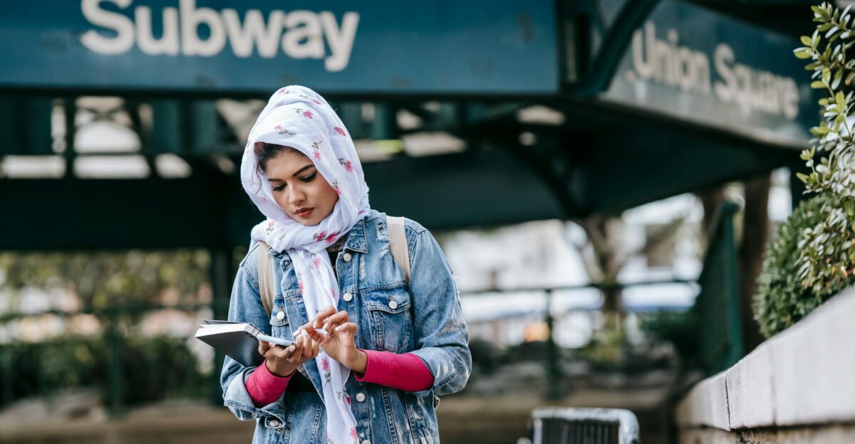 A young woman in hijab using her smartphone near Union Square subway entrance Urban lifestyle scene