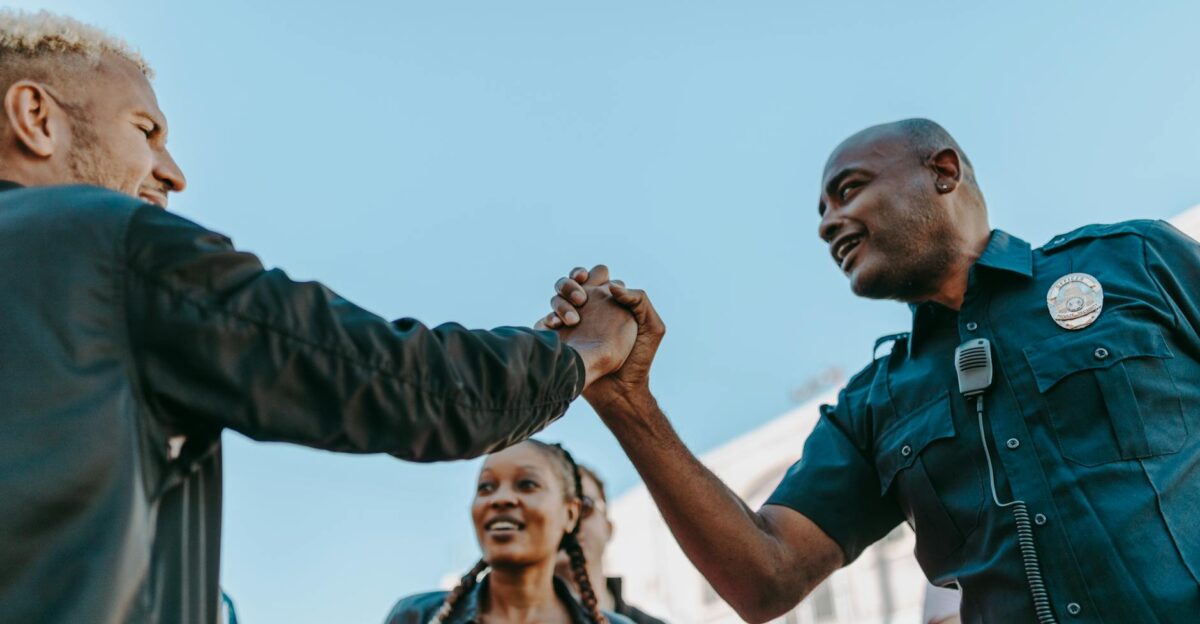 A friendly handshake between a police officer and a civilian during an outdoor community event