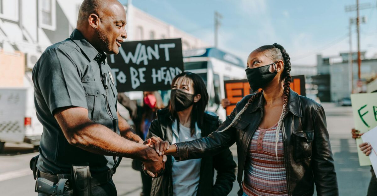 A police officer and a protester shake hands during a peaceful demonstration on a sunny day